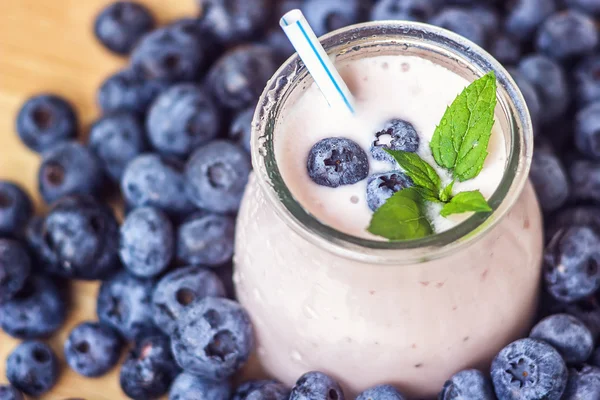 Piękny przekąska blueberry owoce smoothie mleka wstrząsnąć szkło słój z soczyste jagody świeże tło widok z góry jogurt koktajl naturalny detox płyn lody hurtleberry huckleberry winberry fraughan — Zdjęcie stockowe