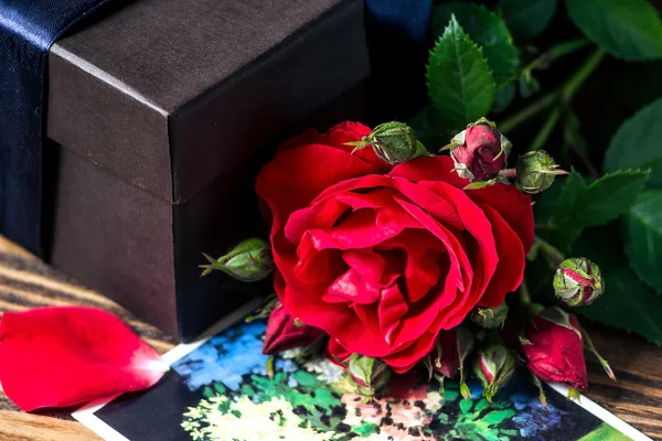 Rode rozen en geschenkdoos op een houten ondergrond — Stockfoto