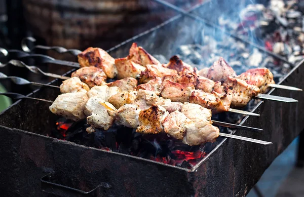 Grilling marinated shashlik preparing on a barbecue grill over charcoal.  Shashlik is a form of Shish kebab popular in Eastern Europe. Shashlyk (meaning  skewered meat) was originally made of lamb. Stock Photo