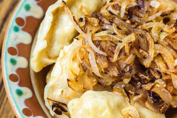 Dumplings met vlees en uien. Selectieve aandacht. Close-up van vers gekookte dumplings met hete kruidenpasta op houten plaat. Chinees eten op rustieke oude vintage houten achtergrond. Stockfoto