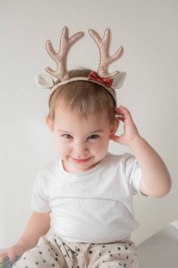 Parlak parlak yağmurlu geyik boynuzları kostümlü küçük kız. Yeni yıl ve noel partisi kutlaması. Noel tatili.