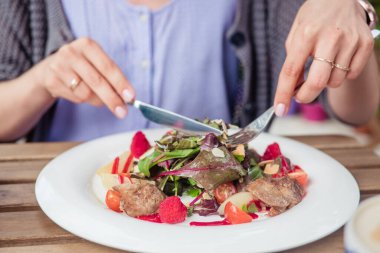 Dışarıdaki kafede salata yiyen kadınların ellerini kapatın.