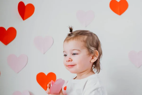 Kleine peuter meisje in rok met harten op de achtergrond met harten vieren Saint Valentines dag. Vakantie decoratie — Stockfoto