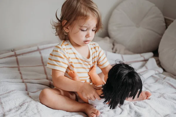 Маленькая девочка играет со своей куклой дома — стоковое фото