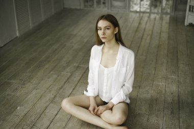 calm beautiful young woman in a white dress at home