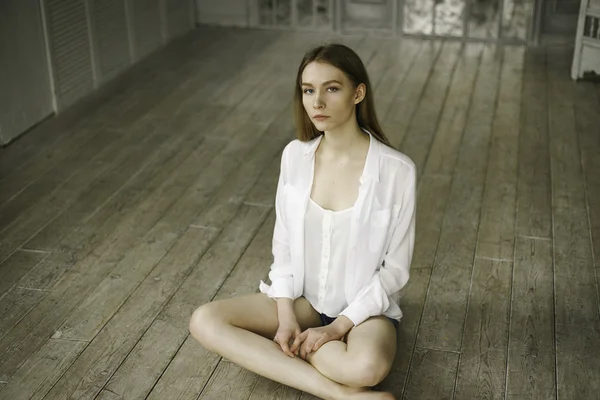 calm beautiful young woman in a white dress at home