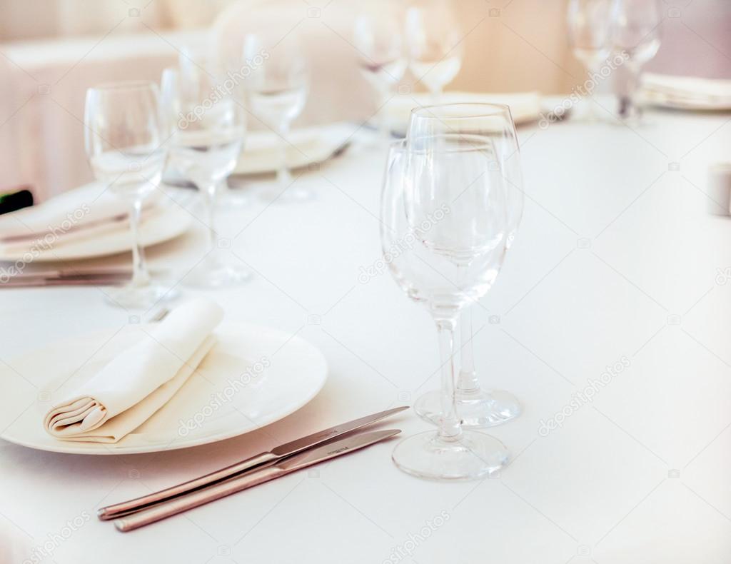 Elegant white wedding table served  with cutlery, napkins and wi