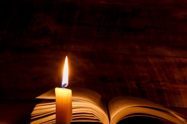 mum ışığında ahşap bir masa üzerine eski kitap