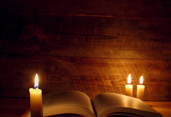 Livro velho em uma mesa de madeira à luz de velas — Fotografia de Stock