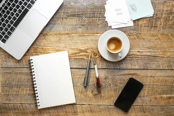 Lugar de trabajo con taza de café, portátil, teléfono en la mesa de madera — Foto de Stock