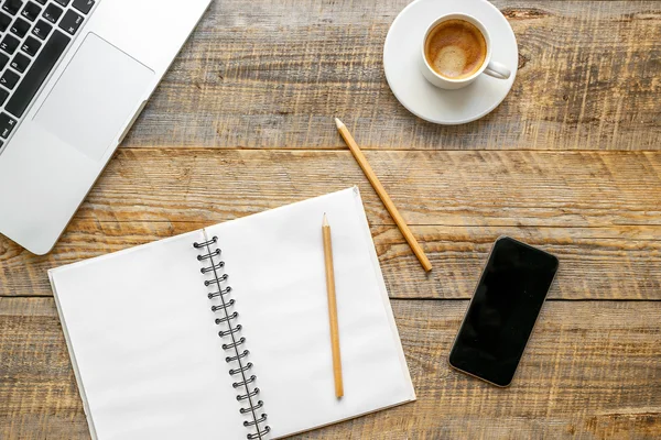 Lugar de trabajo con taza de café, portátil, teléfono en la mesa de madera — Foto de Stock