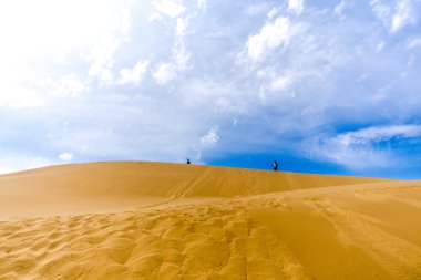 dune üst boyunca yürüyen iki kişi