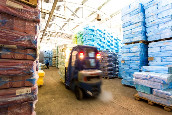 Magazijn met paardrijden vorkheftruck en stapels doos in de fabriek — Stockfoto