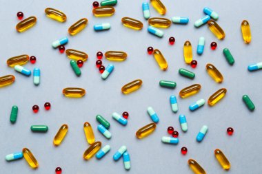 Gri arka planda izole edilmiş renkli tıbbi haplar.