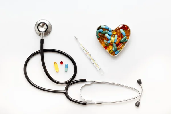 A fehér háttér, szív alakú tabletták sztetoszkóp — Stock Fotó