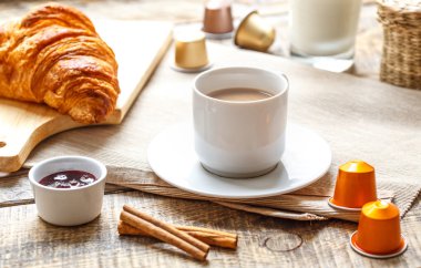 Kahvaltınız, kahveniz ve kruvasanlarınızla ahşap masada.