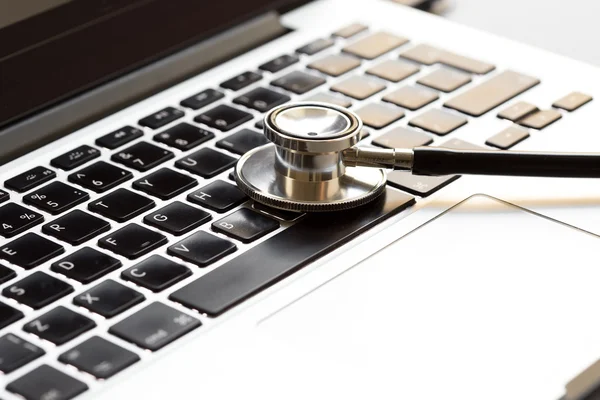 Läkare arbetsplatsen med stetoskop på laptop Stockfoto