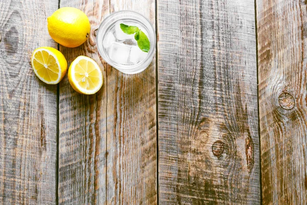 Copo de limonada com limões na mesa de madeira — Fotografia de Stock