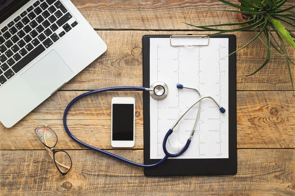 Medico sul posto di lavoro con uno stetoscopio a tavolo di legno — Foto Stock