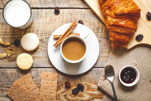 Desayuno con café, galletas y croissants sobre mesa de madera — Foto de Stock