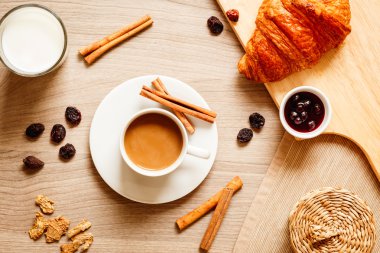 Kahvaltınız, kahveniz ve kruvasanlarınızla ahşap masada.