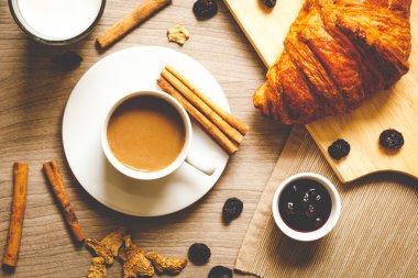 Kahvaltınız, kahveniz ve kruvasanlarınızla ahşap masada.