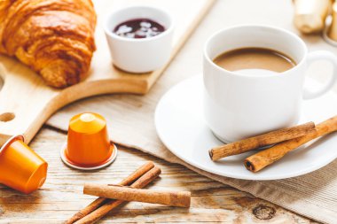Kahvaltınız, kahveniz ve kruvasanlarınızla ahşap masada.