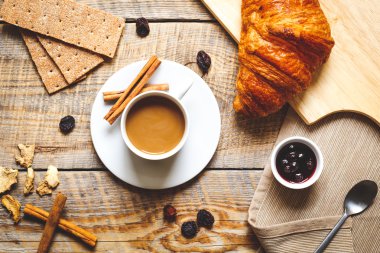 Kahve, kraker ve ahşap masa üzerinde kruvasan kahvaltı