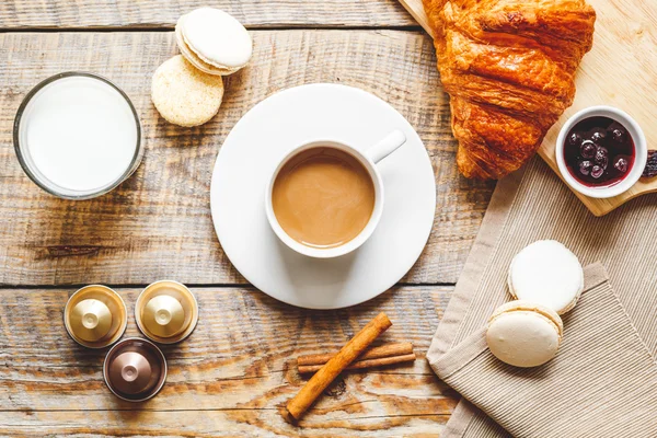 Desayuno dulce con café, macarrones y cruasanes sobre mesa de madera — Foto de Stock