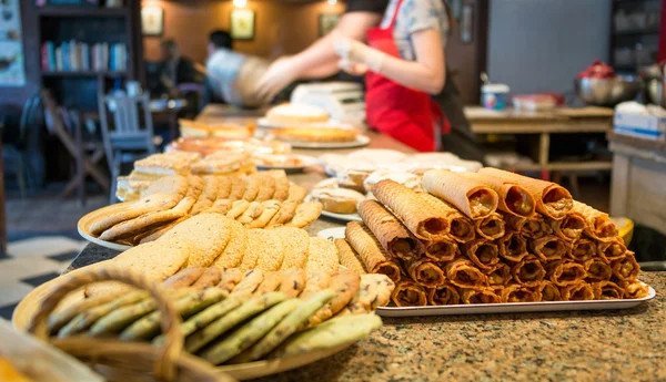 Different types of sweet pastries on plates at counter cafe — Stock Photo, Image