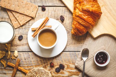Kahvaltınız, kahveniz ve kruvasanlarınızla ahşap masada.