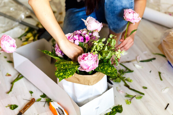 Florist making a bouguet of peonies