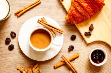 Kahvaltınız, kahveniz ve kruvasanlarınızla ahşap masada.