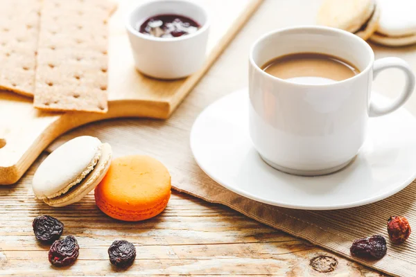 Desayuno dulce con café, macarrones y cruasanes sobre mesa de madera — Foto de Stock