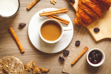Kahvaltınız, kahveniz ve kruvasanlarınızla ahşap masada.