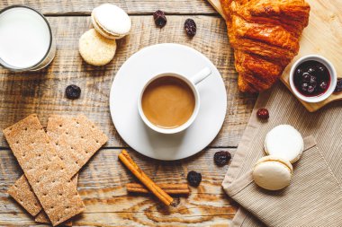 Kahvaltınız, kahveniz ve kruvasanlarınızla ahşap masada.