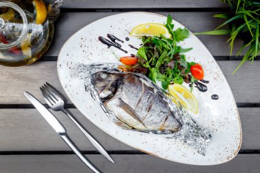 ahşap masa restoranda beyaz tabakta balık pişmiş