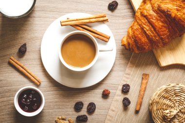 Kahvaltınız, kahveniz ve kruvasanlarınızla ahşap masada.