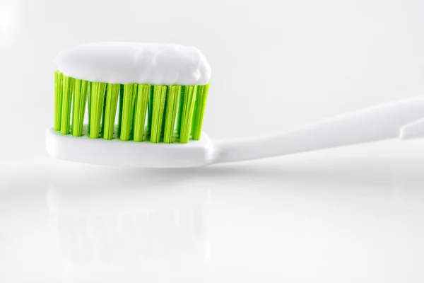 Sqweezed green toothbrush on white background — Stock Photo, Image