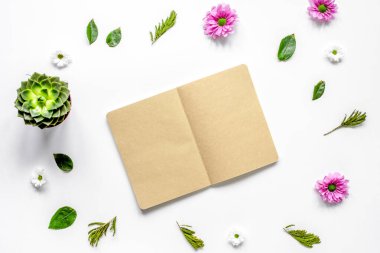 Beyaz masa arkaplanındaki çiçek yapraklı defter. Üst görünüm maketi