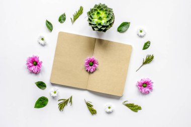 Beyaz masa arkaplanındaki çiçek yapraklı defter. Üst görünüm maketi
