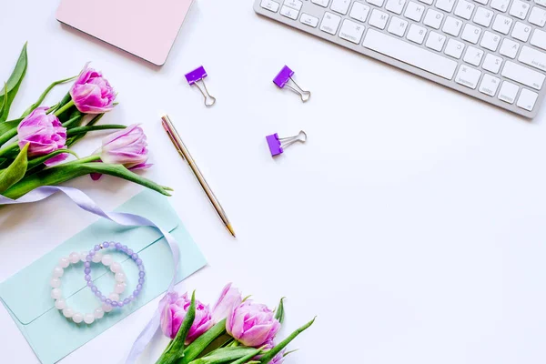 Flowers on trendy desk in office white background top view mock up