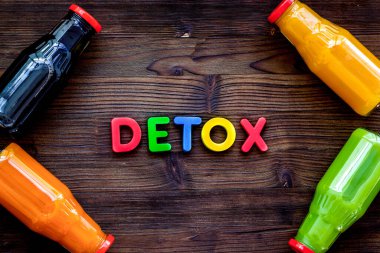 Tahta arka planda detoks diyeti için şişelerdeki taze organik sıvılar.