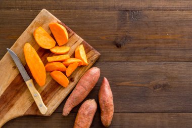 Kesme tahtasında dilimlenmiş tatlı patates, üst manzara.