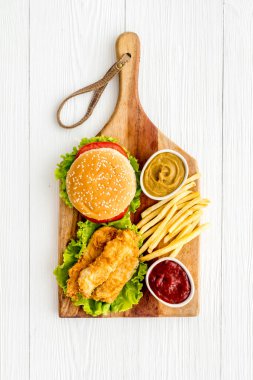 Fast food seti. Tahta kesme tahtasının üzerinde patates kızartması ve lezzetli bir hamburger.