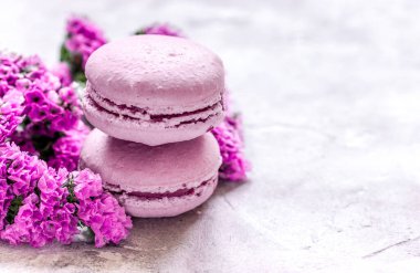 Bayan Morning, badem kurabiyesi ve leylak rengi çiçeklerle dolu beyaz masa arkası.