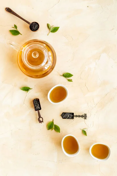 Hojas verdes de té con tetera y tazas, vista superior. Concepto de ceremonia del té. —  Fotos de Stock