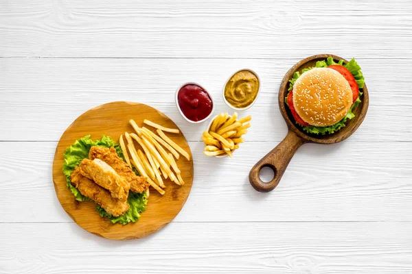 Set de comida rápida. Deliciosa hamburguesa con papas fritas en tabla de cortar de madera — Foto de Stock