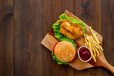 Fast food seti. Tahta kesme tahtasının üzerinde patates kızartması ve lezzetli bir hamburger.