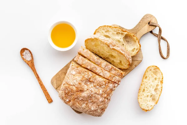 Pão ciabatta fatiado com óleo sobre placa de corte, vista superior — Fotografia de Stock